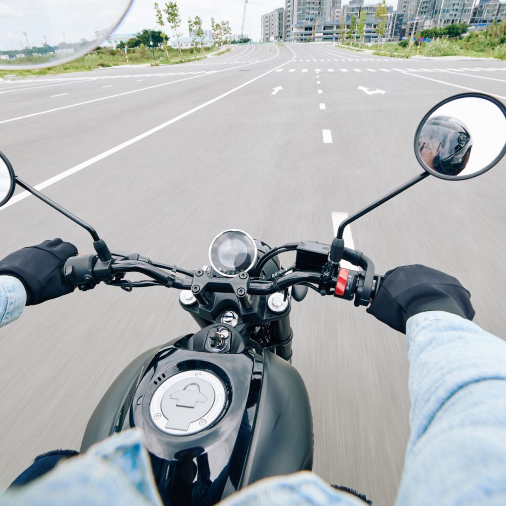 View over handlebar of motorcycle of young man riding fast on highway